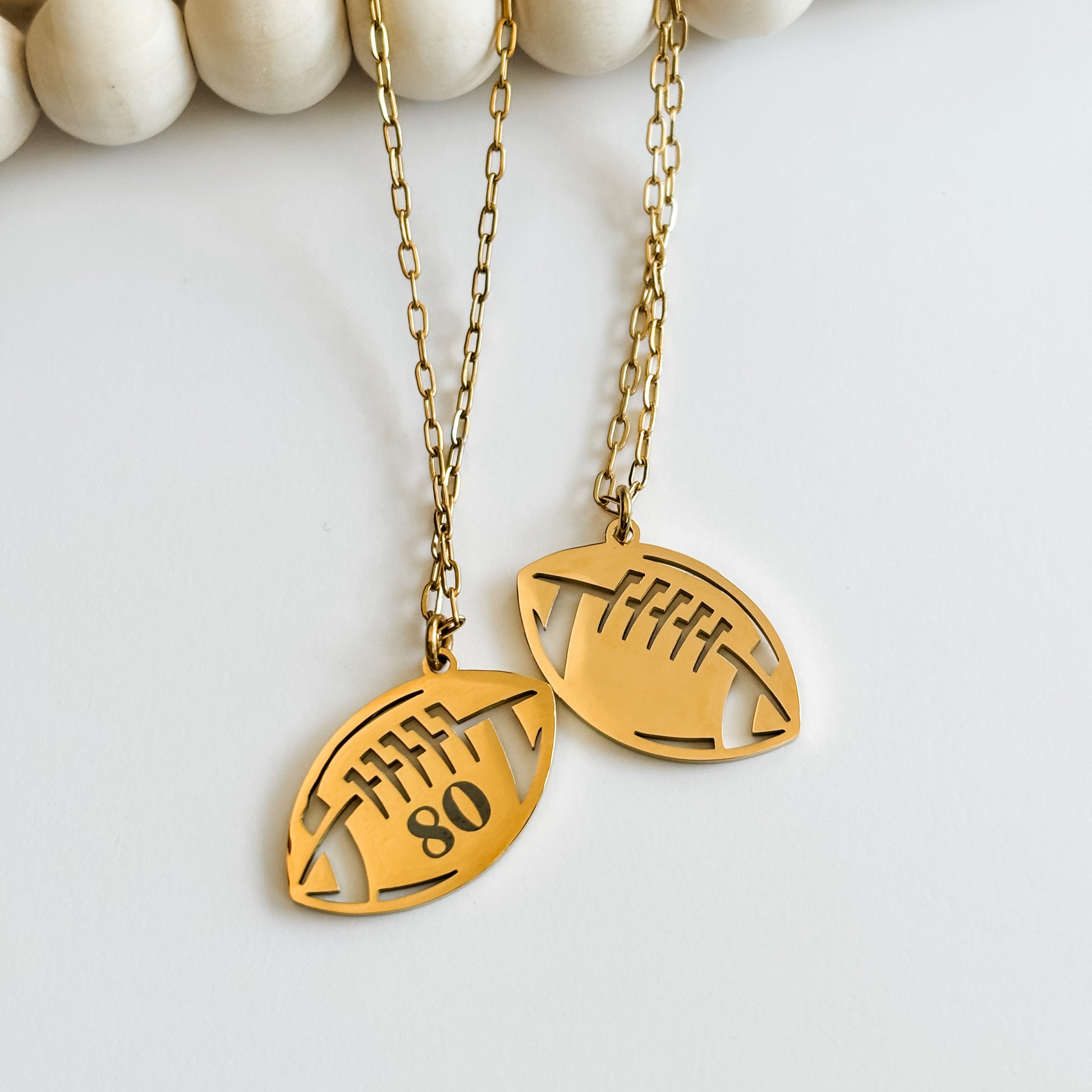 Gold football-shaped pendant necklace with cut-out design on a white background