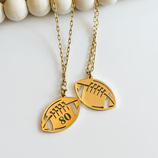 Gold football-shaped pendant necklace with cut-out design on a white background